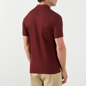 Model wearing Burberry red cotton polo shirt, back view, styled with beige trousers