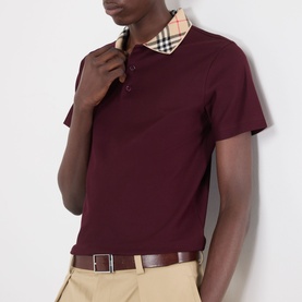 Model wearing Burberry Evan Check Polo Shirt in Vineyard Red with check collar detail, styled with beige chinos and brown belt.