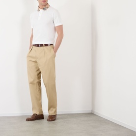 Model wearing Burberry white cotton polo shirt with check collar, styled with beige chinos and brown leather loafers.