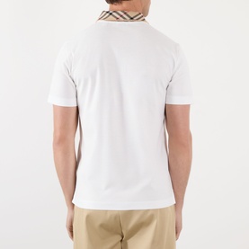 Model wearing Burberry white cotton polo shirt, back view, with signature house check collar trim and beige trousers.