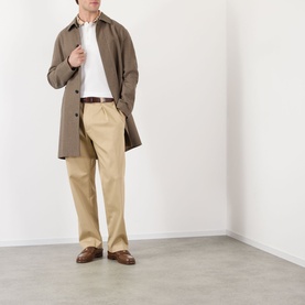 Model wearing Burberry white cotton polo, styled with taupe overcoat, beige trousers and brown leather loafers.