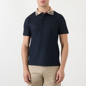 Model wearing Burberry Evan Burberry Check Polo Shirt in navy with iconic check collar, short sleeves, and three-button placket, styled with beige
