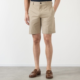 Model wearing Burberry Charlton Embroidered Logo Chino Shorts in Saltmarsh Beige, slim-leg above-the-knee cut with pressed creases, styled with tan