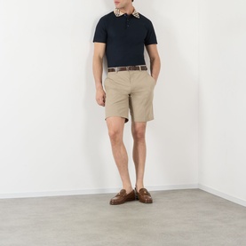 Model wearing Burberry Charlton Embroidered Logo Chino Shorts in saltmarsh beige, styled with navy polo shirt and brown loafers