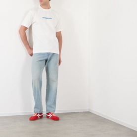 Model wearing Burberry white cotton T-shirt with small chest graphic, styled with light wash jeans and red trainers