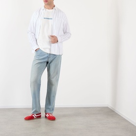 Model wearing Burberry white cotton T-shirt with striped overshirt, light blue jeans and red trainers.
