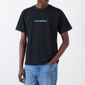 Model wearing Burberry Ryan Big Logo T-Shirt in black, with teal chest logo print, crew neck, short sleeves. Styled with blue jeans.