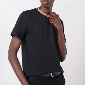 Model wearing Burberry Ryan Signature Check T-Shirt in black with signature check taping at crew neck, styled with black belt.