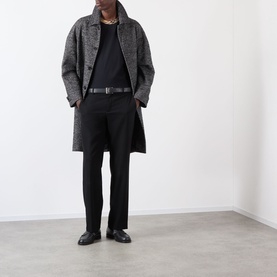 Model wearing Burberry Ryan Signature Check T-Shirt in black, styled with grey herringbone overcoat, black trousers, belt and loafers.