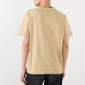 Model wearing Burberry Ryan Check-Collar T-Shirt in sand, rear view showing signature check collar detail and short sleeves, styled with dark jeans.