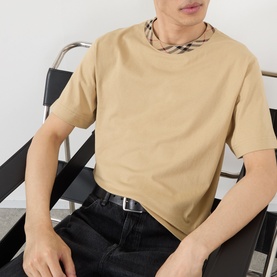 Model wearing Burberry Ryan Check-Collar T-Shirt in sand, featuring signature check collar detail, styled with black jeans and belt.