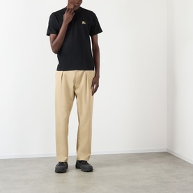 Model wearing Burberry Seth Embroidered Logo T-Shirt in black with chest logo, styled with beige trousers and black shoes.
