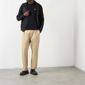 Model wearing Burberry Seth Embroidered Logo T-Shirt in black with black zip jacket, beige trousers and black trainers.