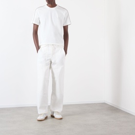Model wearing Burberry Seth Logo Check T-Shirt in white with check piping detail, styled with white wide-leg trousers and white trainers.