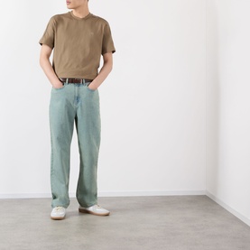 Model wearing Burberry Seth Check Piping T-Shirt in Finch Brown with light blue wide-leg jeans and white low-top trainers.