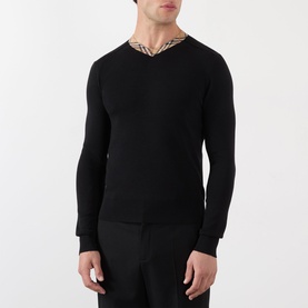 Model wearing Burberry black wool V-neck jumper with signature check collar trim, styled with dark trousers.