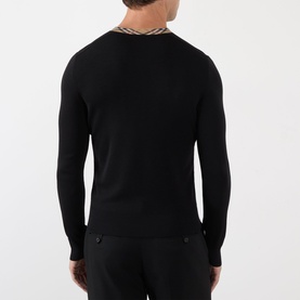 Model wearing Burberry black wool V-neck jumper, back view, with signature check trim at collar and dark trousers.