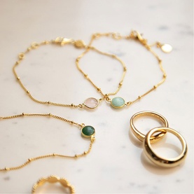 Daisy Jewellery Healing Stone Bobble Bracelet in 18ct Gold Plate with amazonite stone, styled with additional gold bracelets and rings on marble