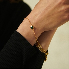 Model with Daisy Jewellery Healing Stone Bobble Bracelet in 18ct gold plate with green aventurine stone, worn on wrist with black sleeve visible.