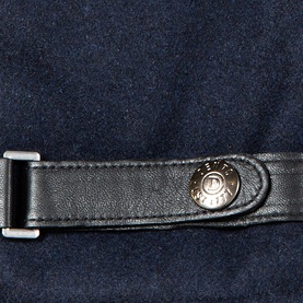 Dents gloves in navy and black leather, close-up of silver snap button fastening detail on cuff strap