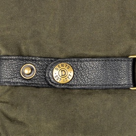 Dents gloves close-up showing black leather strap with gold-tone press stud and branded logo detail against olive fabric.