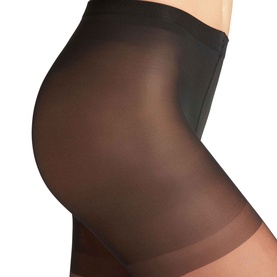 Model wearing Falke black shaping tights, showing smoothing control panel waistband and sheer leg detail.