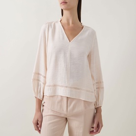 Model wearing InWear Vanilla blouse with V-neck, sheer panel trim on hem and sleeves, styled with light beige trousers.