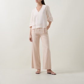 Model wearing InWear Vanilla blouse with V-neck and balloon sleeves, styled with wide-leg blush trousers and flat sandals.