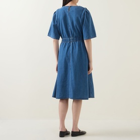 Model wearing InWear Glenn Denim Dress in Faded Blue, midi length with elasticated waist and flared skirt. Back view, styled with black flat shoes.