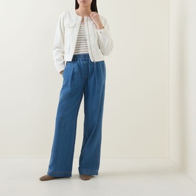 Model wearing InWear Gladys Zip Denim Jacket in Ecru Melange, collarless with chest pockets, styled with wide-leg blue trousers and a striped top.