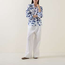 Model wearing InWear Cielle Illuminating Florals Blouse in Blue Blurr with white wide-leg trousers and brown flat shoes.