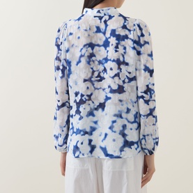 Model wearing InWear Cielle Illuminating Florals Blouse in Blue Blurr, back view, long sleeves with elasticated cuffs, styled with white trousers
