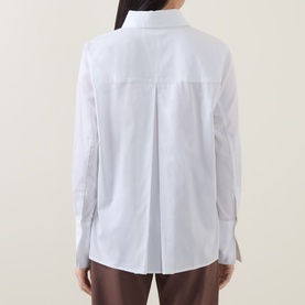 Model wearing InWear Vex Pleated Shirt in Pure White, rear view showing inverted back pleat and extended cuffs, styled with brown trousers
