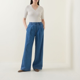 Model wearing InWear Glenn Pleated Denim Trousers in Faded Blue, wide-leg with elasticated waist, styled with a white stripe knit top