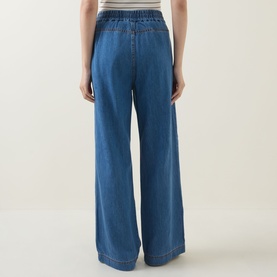 Model wearing InWear Glenn Pleated Denim Trousers in Faded Blue, wide-leg silhouette with elasticated waistband, rear view