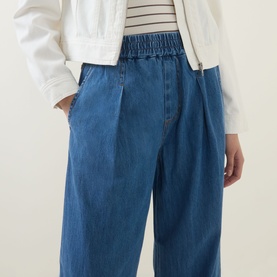 Model wearing InWear Glenn Pleated Denim Trousers in Faded Blue, wide-leg with elasticated waist, styled with a white jacket and striped top.