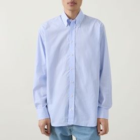 Model wearing Kempt Stripe Single-Cuff Shirt in blue and white, featuring button-down collar, long sleeves, and curved hemline.