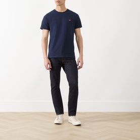 Model wearing Levis Original Housemark Logo T-Shirt in blue, crew neck, short sleeves, styled with dark jeans and white trainers.