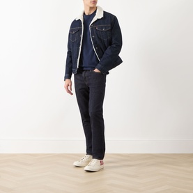 Model wearing Levi's Original Housemark Logo T-Shirt in blue, styled with dark denim sherpa jacket, navy jeans, and cream trainers.