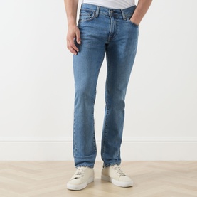 Model wearing Levis 511&trade; Slim Leg Jeans in A Step Ahead mid-blue wash, slim fit with five-pocket styling, paired with white trainers.