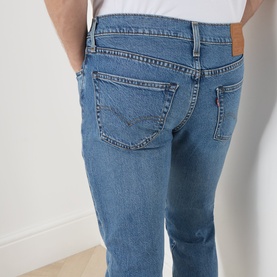 Model wearing Levi's 511 Slim Leg Jeans in A Step Ahead blue denim, showing rear five-pocket detail and branded leather badge patch.