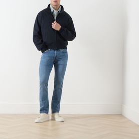 Model wearing Levi's 511&trade; Slim Leg Jeans in A Step Ahead mid-blue wash, styled with a navy jacket and white trainers.