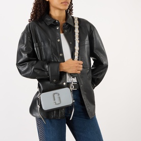 Model carrying Marc Jacobs The Colourblock Chain Snapshot in Wolf Grey Multi Stripe, silver-tone hardware, woven strap, worn crossbody over black
