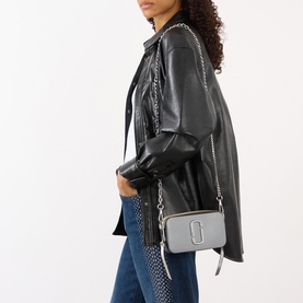 Model carrying Marc Jacobs The Colourblock Chain Snapshot in wolf grey multi stripe, silver-tone chain strap, worn crossbody over black leather
