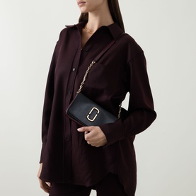 Model carrying Marc Jacobs The Snapshot On Chain Wallet in black multi, gold curb chain strap, gold-toned hardware, styled with dark burgundy