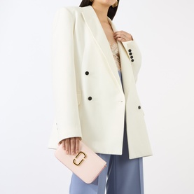 Model carrying Marc Jacobs The Snapshot On Chain Wallet in powder pink multi, gold-toned hardware, styled with ivory blazer and blue trousers