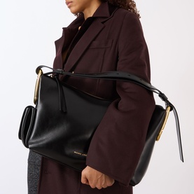 Model carrying Marc Jacobs The Scene Large Shoulder Bag in black smooth leather with gold-tone hardware, styled with a dark burgundy coat