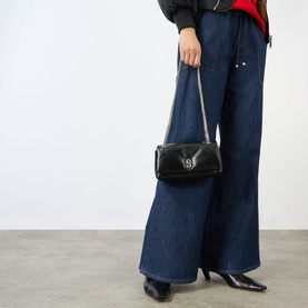 Model carrying Marc Jacobs Scene Chain Mini Bag in black leather with gunmetal hardware, styled with wide-leg jeans and black heels.