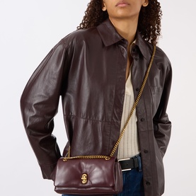 Model carrying Marc Jacobs The Dual Chain Mini Bag in Dark Port, gold-tone chain strap, turn-lock closure, smooth leather, styled with dark leather
