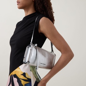 Model carrying Marc Jacobs Scene Small Shoulder Bag in silver metallic leather with zip-top and silver-toned hardware, styled with black top and